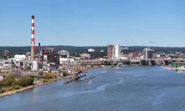 Bridgeport skyline across the water, with a red-and-white power plant smokestack on the left